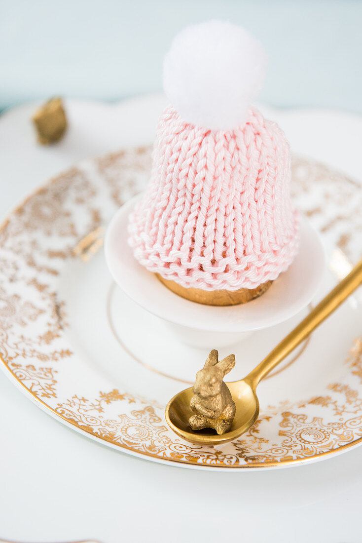 Knitted bobble-hat egg cosy on vintage-style plates