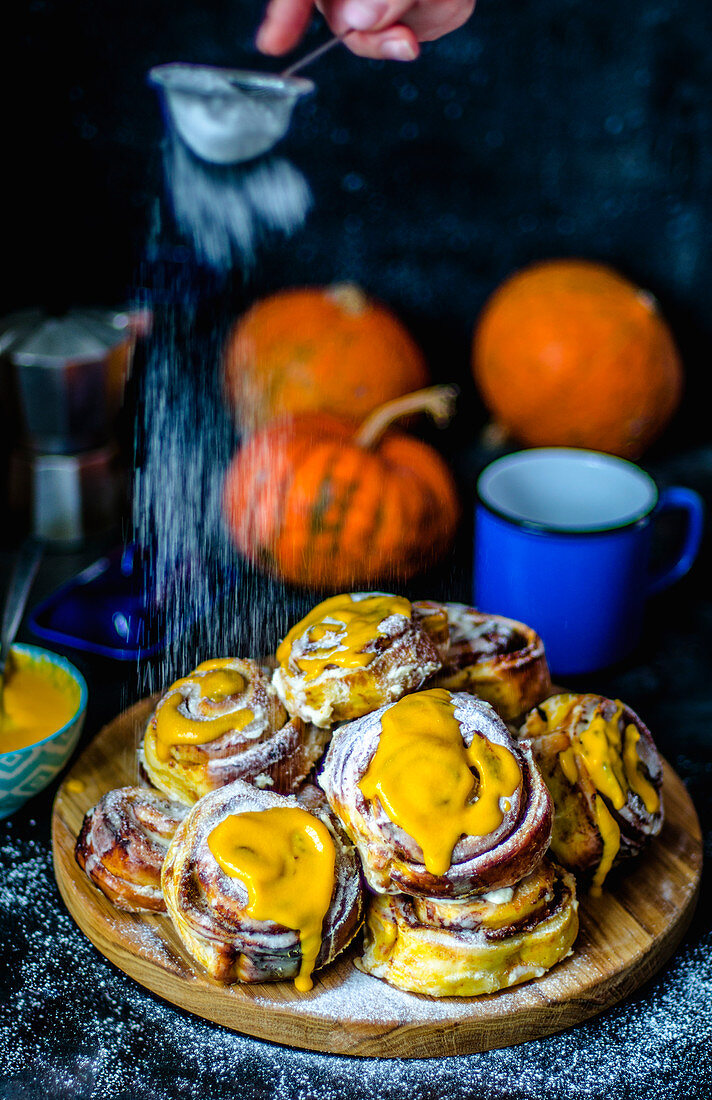 Cinnabons with pumpkin and pumpkin puree sauce with cream and powdered sugar