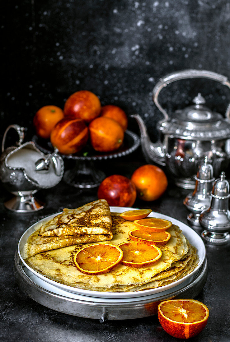 Custard pancakes on kefir with slices of red orange and fresh red oranges