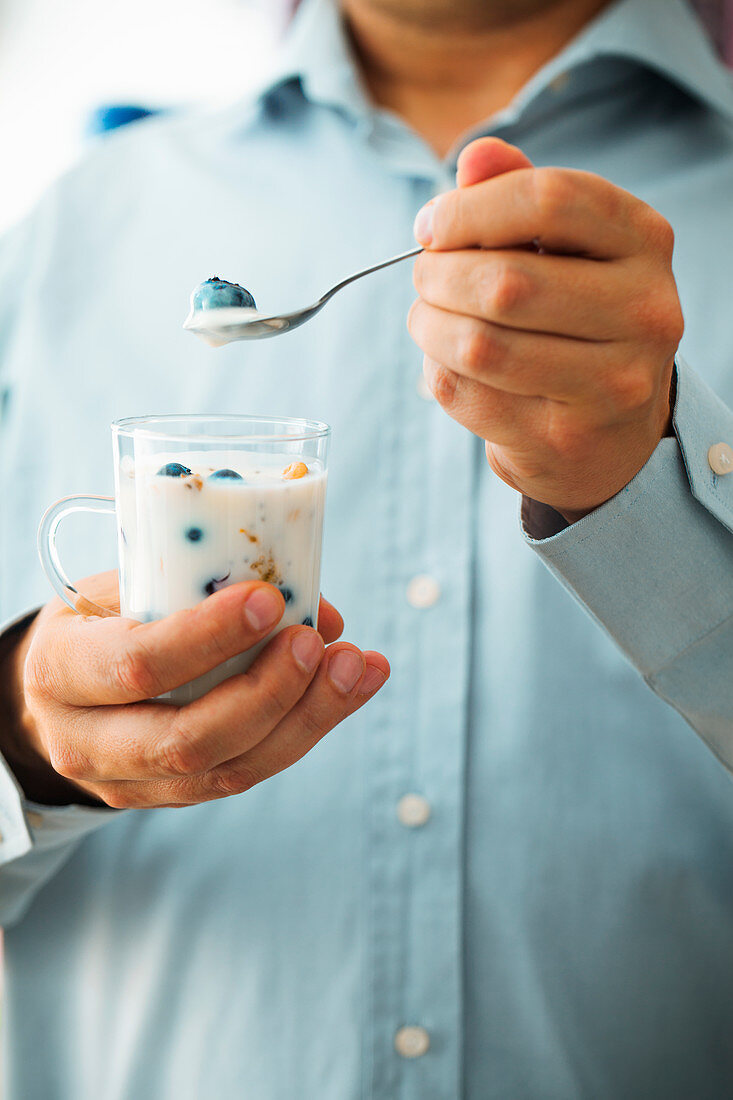 Man eating yogurt with fruit and seeds