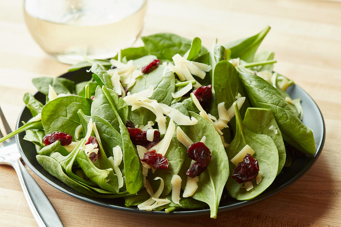 A spinach salad with goat's cheese cheddar and dried cranberries