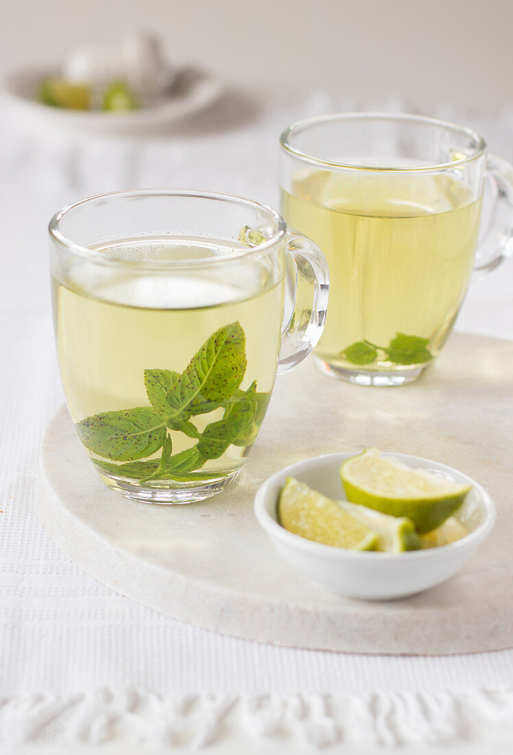 Mint tea in two clear cups on white