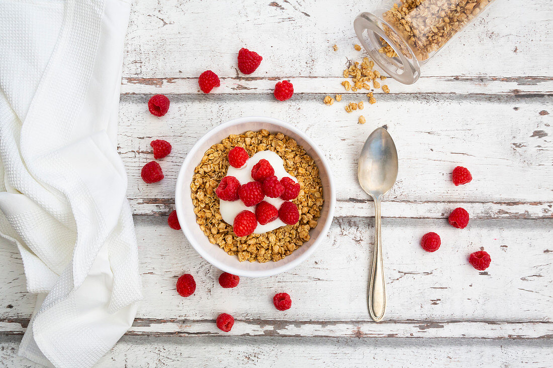 Granola with yoghurt and raspberries in a bowl (seen from above)