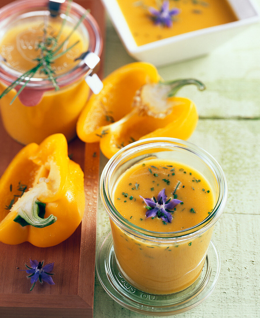 Yellow pepper soup with borage flowers in jars