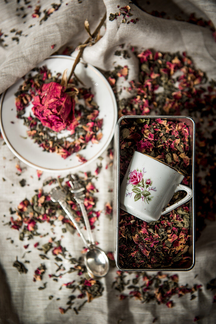 Tasse mit Blumenmotiv in einer Blechdose mit Rosentee