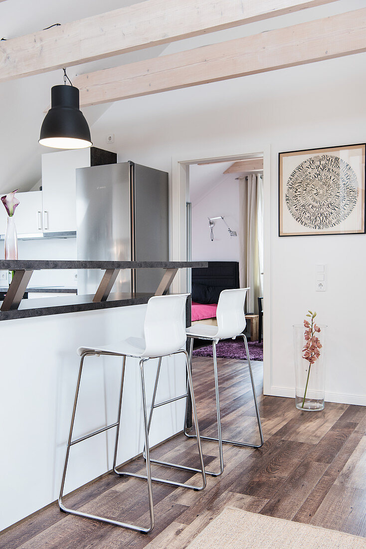 Bar stools at counter in white open-plan kitchen