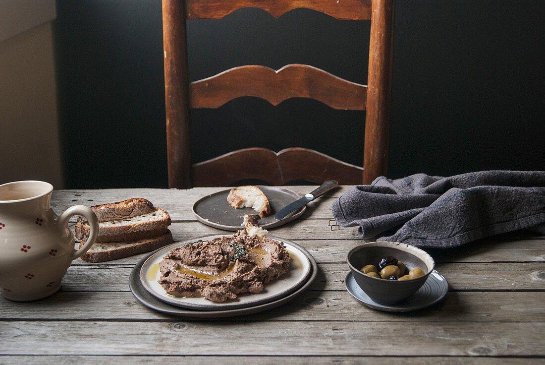 Lentil and shiitake cream with bread and olives on a rustic wooden table