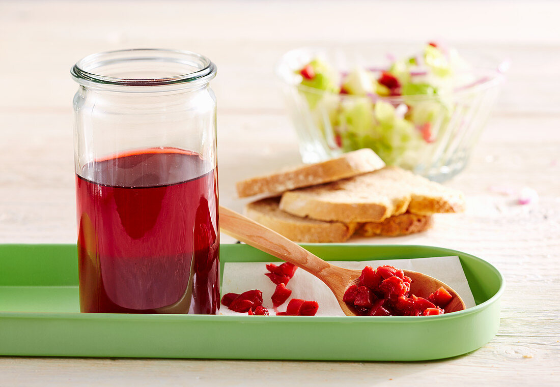 Homemade sour cherry vinegar in a glass, with salad and white bread
