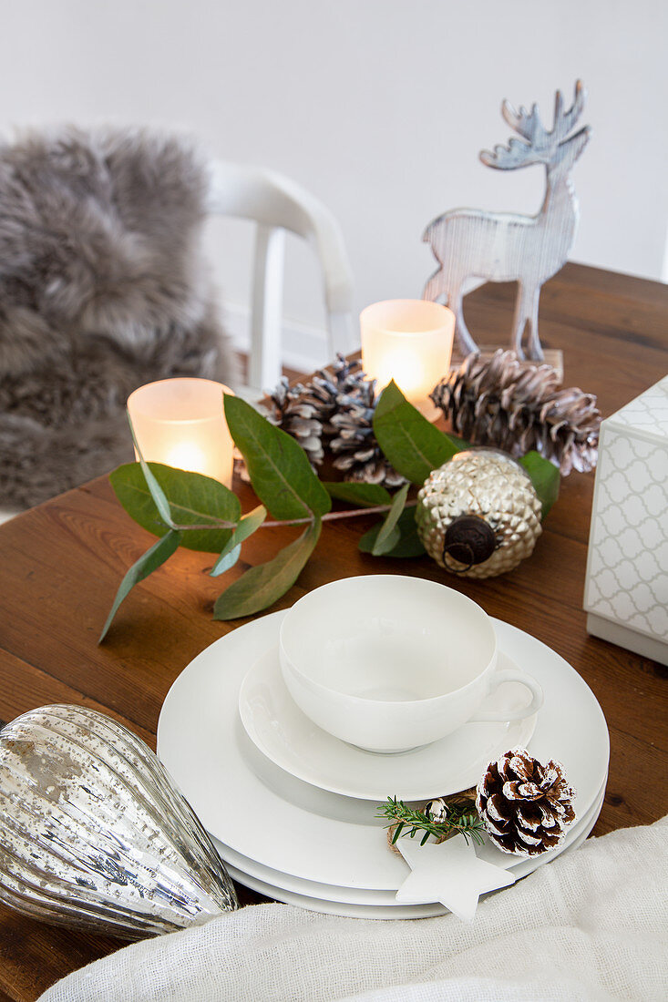 Weißes Geschirr und Weihnachtsdekoration auf Holztisch