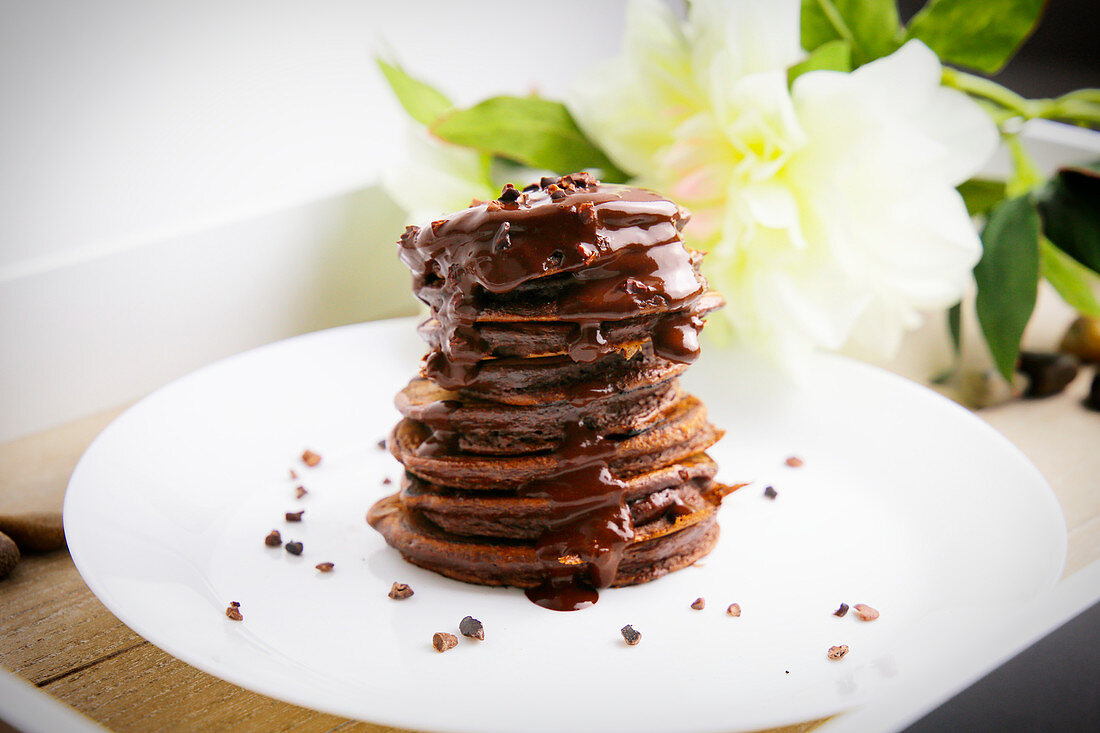 A stack of chocolate pancakes with chocolate sauce