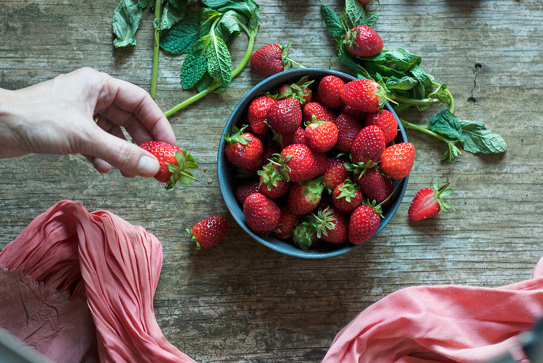 Hand taking delicious strawberry from bowl