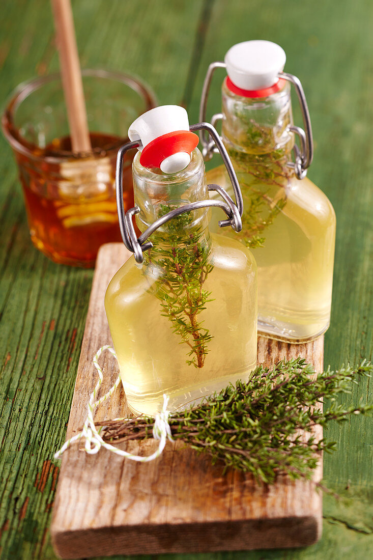 Homemade thyme vinegar with honey in small glasses on a wooden board