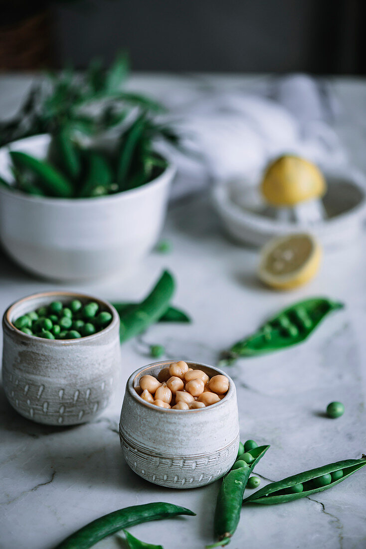 Close-up shot of small jars full of ripe peas standing on white marble tabletop