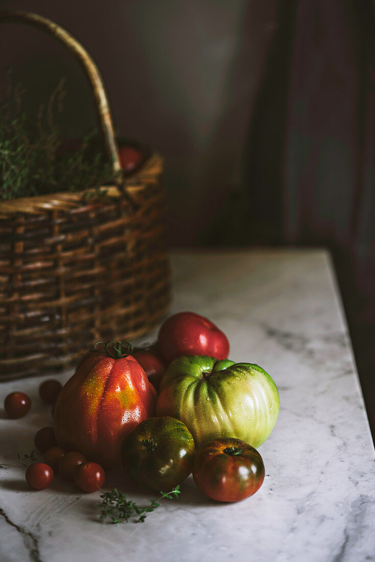Frische Tomaten und Weidenkorb auf Marmortisch