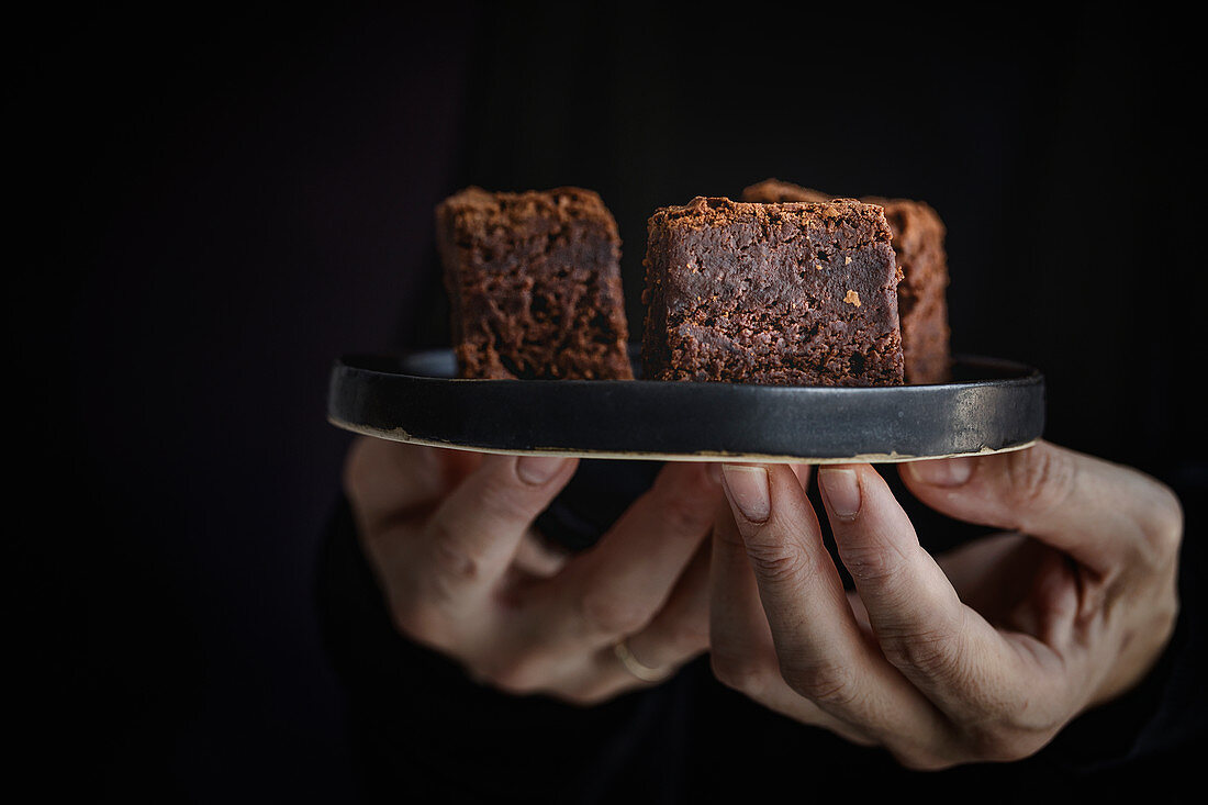 Hände halten Teller mit Schokoladenbrownies