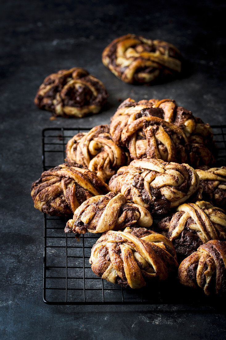 Closeup shot of bunch of delicious chocolate buns lying on metal grating in dark room