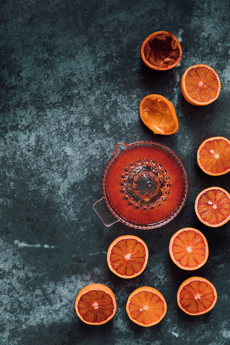 Bllod oranges cut in half, squeezed to show beautiful red juice