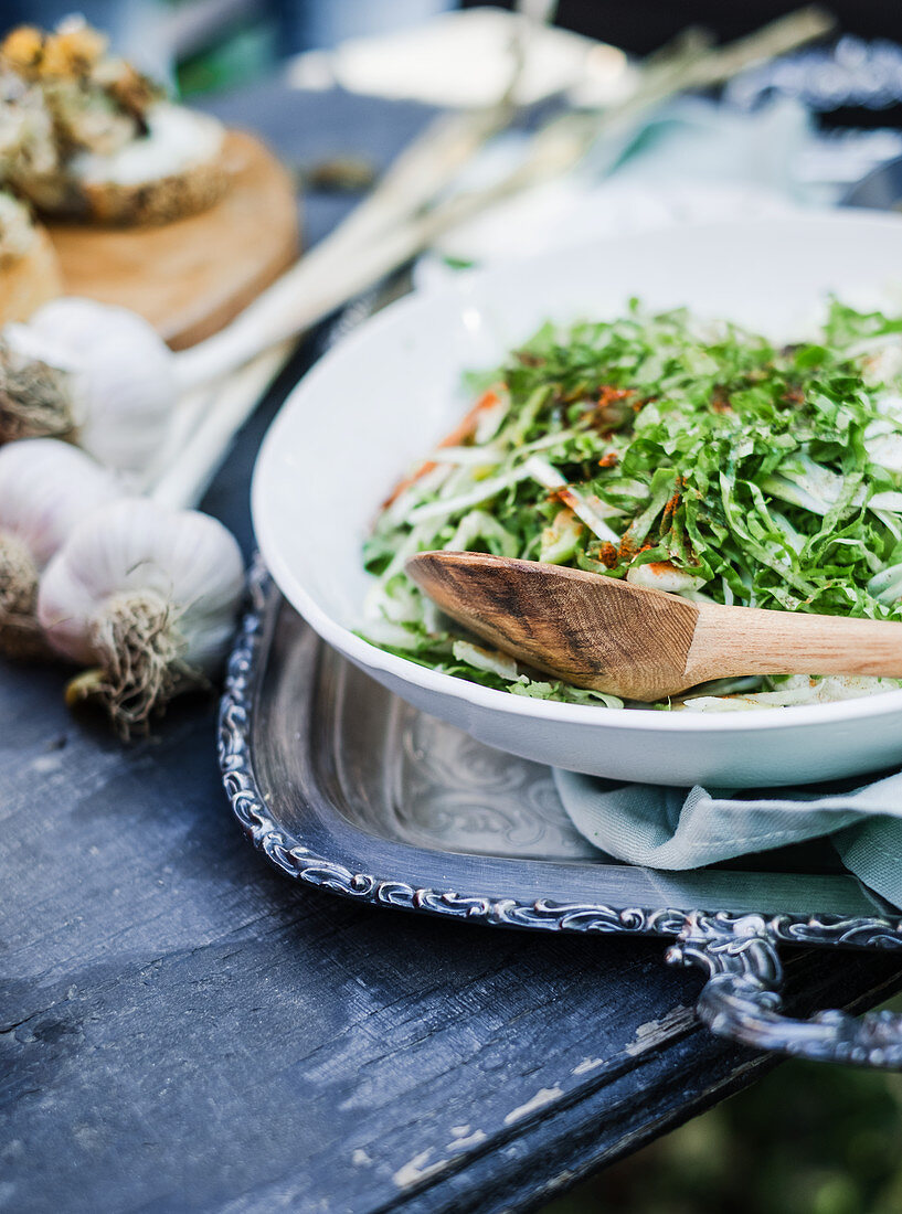 Salad leaves and garlic on a wooden table outdoors