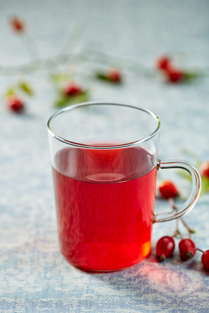 Rosehip tea in a glass cup with fresh rosehips