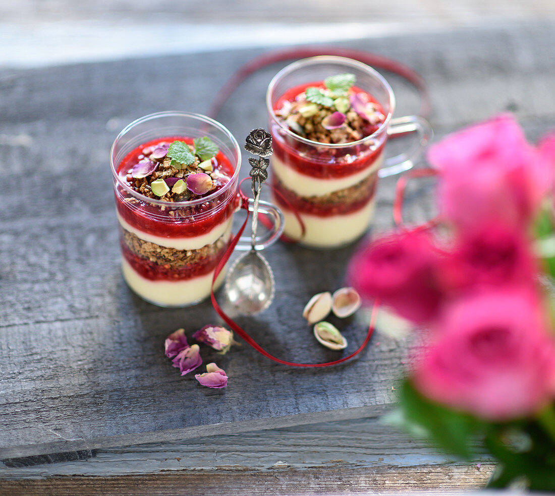 Vegan layered dessert in jars with granola, vanilla yoghurt cream and raspberries