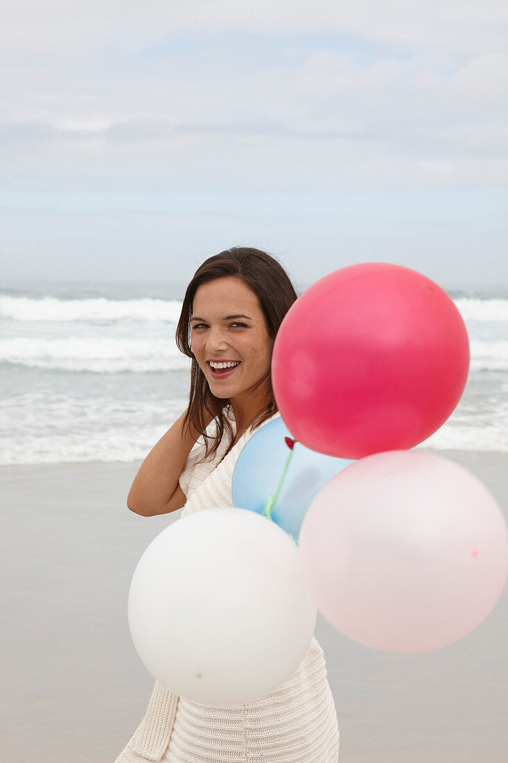 A brunette woman wearing a short-sleeved cardigan and holding a balloon