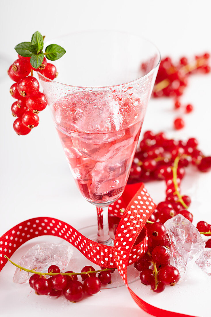Homemade redcurrant liqueur with a ribbon and fresh berries