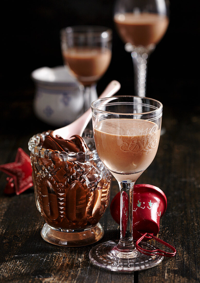 Homemade gingerbread liqueur in a glass with nut-nougat cream spread behind it