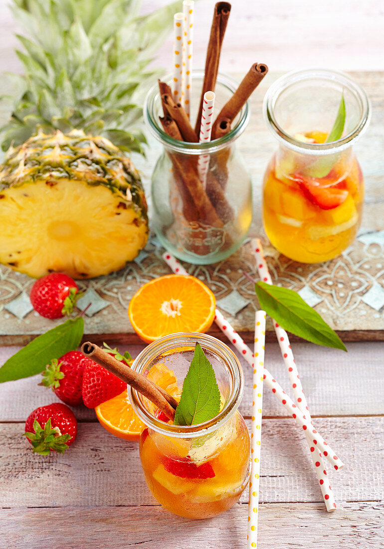 Summer pineapple rum punch with strawberries, mandarins and cinnamon