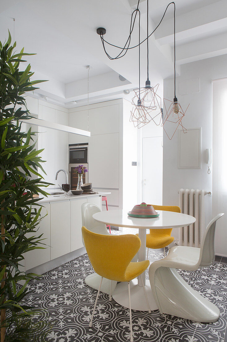 Round table and yellow and white classic chairs next to kitchen counter