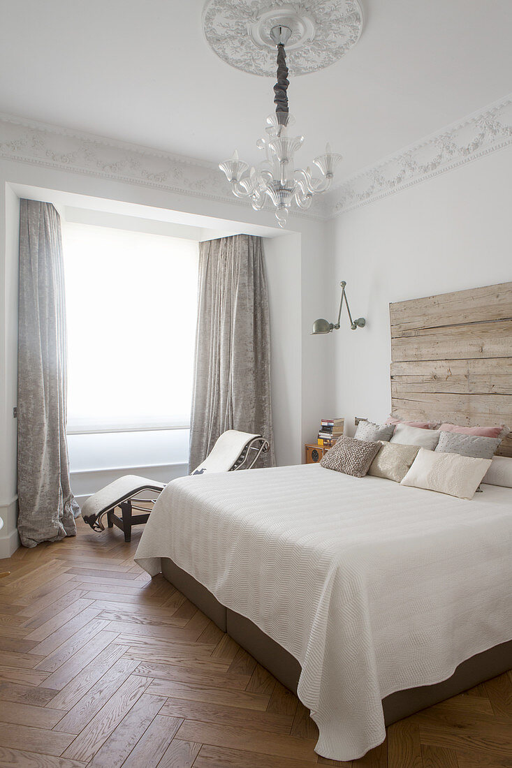 Double bed with rustic wooden headboard and lounger in bedroom