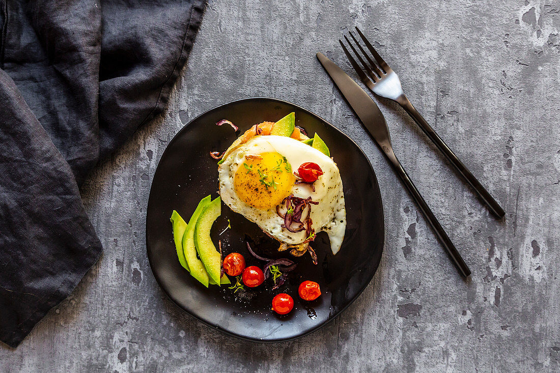 Toast with salmon, avocado, fried egg, tomatoes, red onion and cress