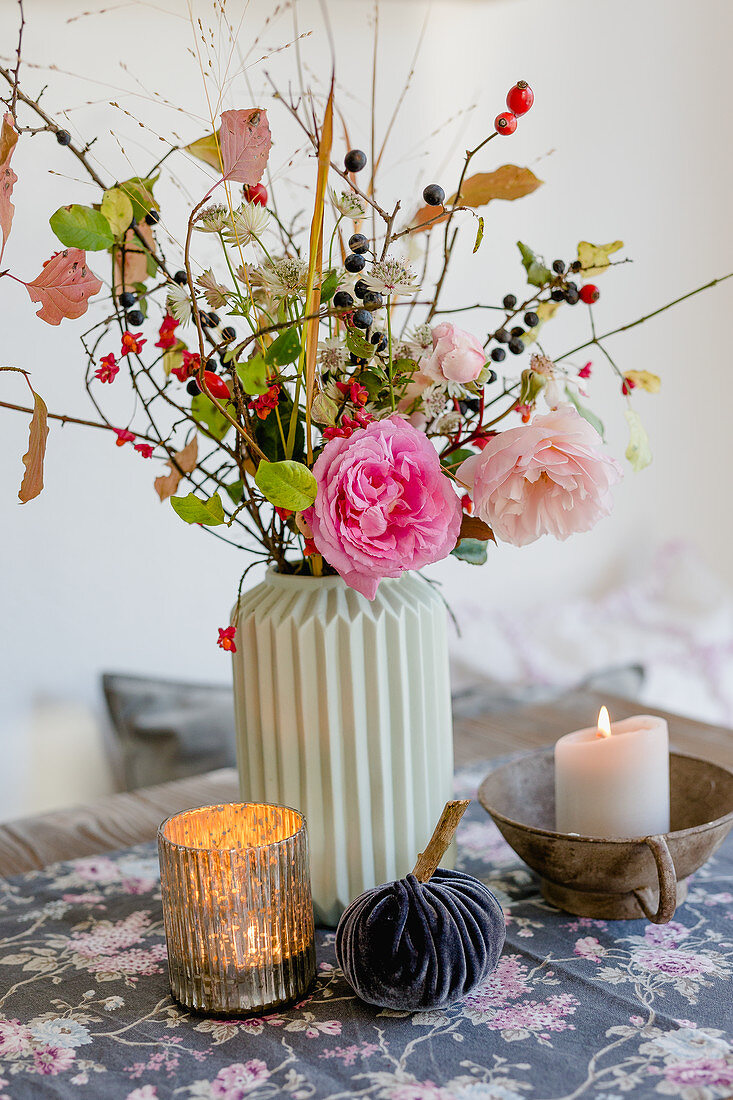 Autumn bouquet of roses, rose hips, astrantias and branches of sloes and spindle fruits