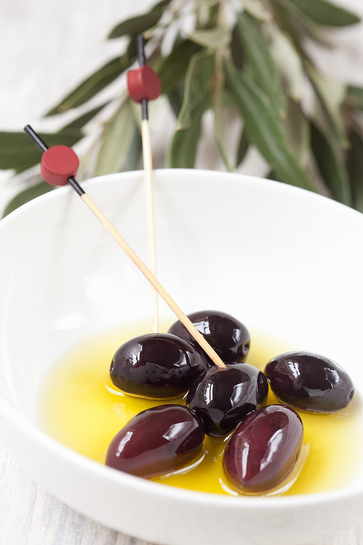 Black kalamata olives in bowls with wooden skewers