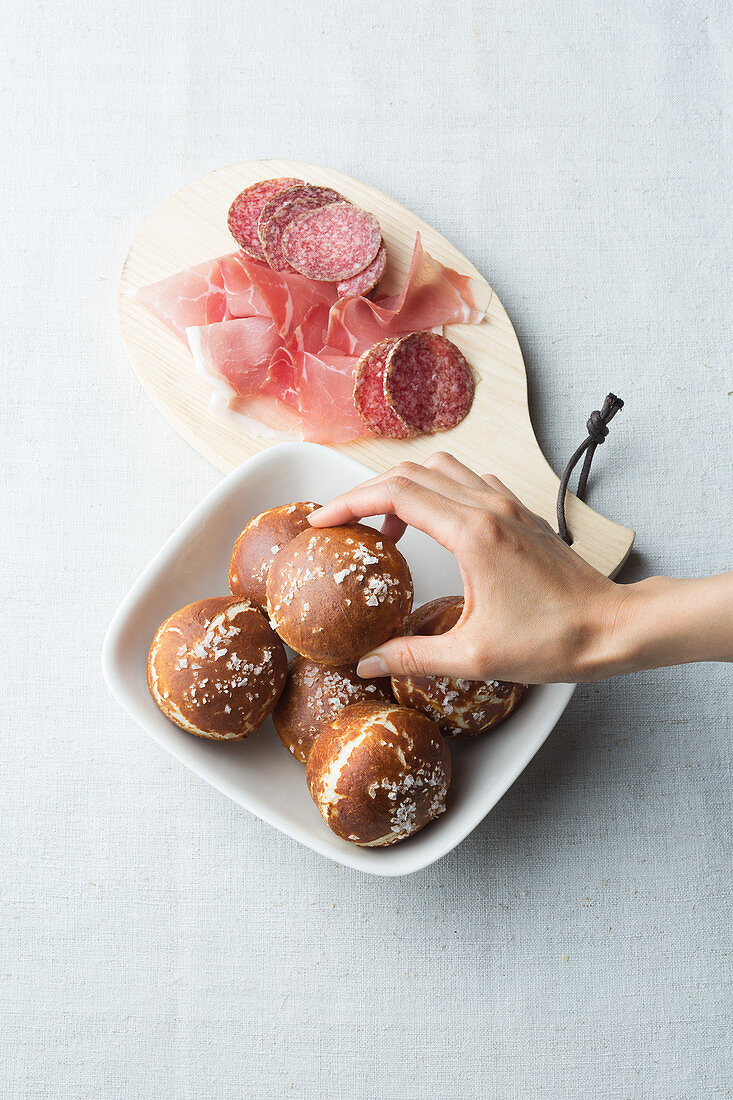 Laugenbrötchen serviert mit Salami und Schinken