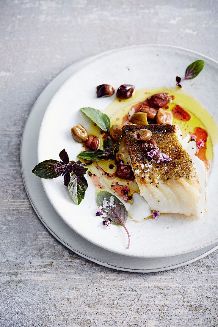 Fried cod with olives and a sprig of basil