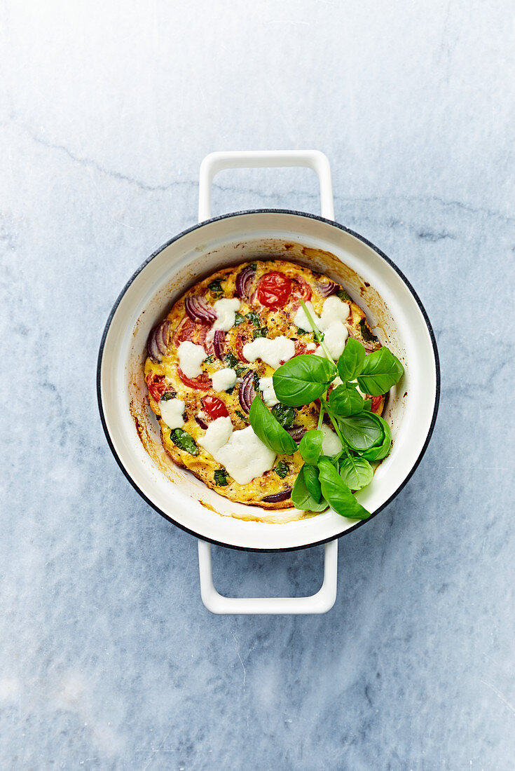 Cherry tomato and red onion frittata with mozzarella and basil leaves