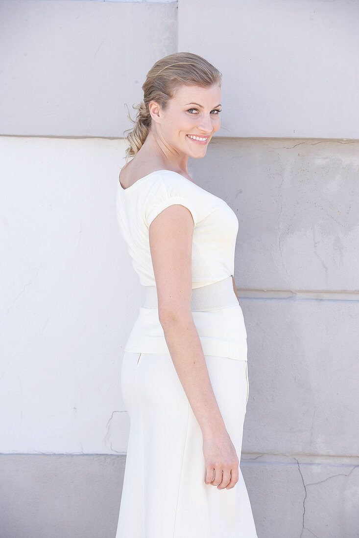 A blonde woman wearing a white shirt and a white skirt