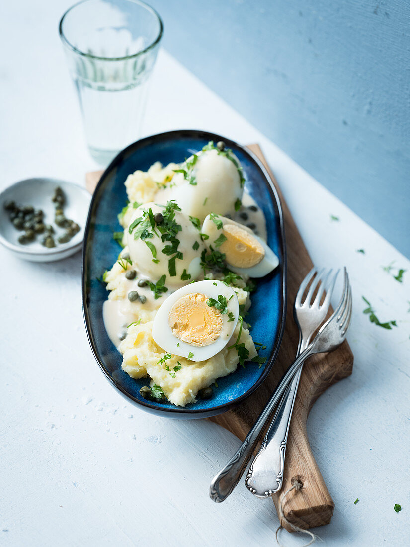 Hard-boiled eggs with a caper sauce on a bed of mashed potatoes