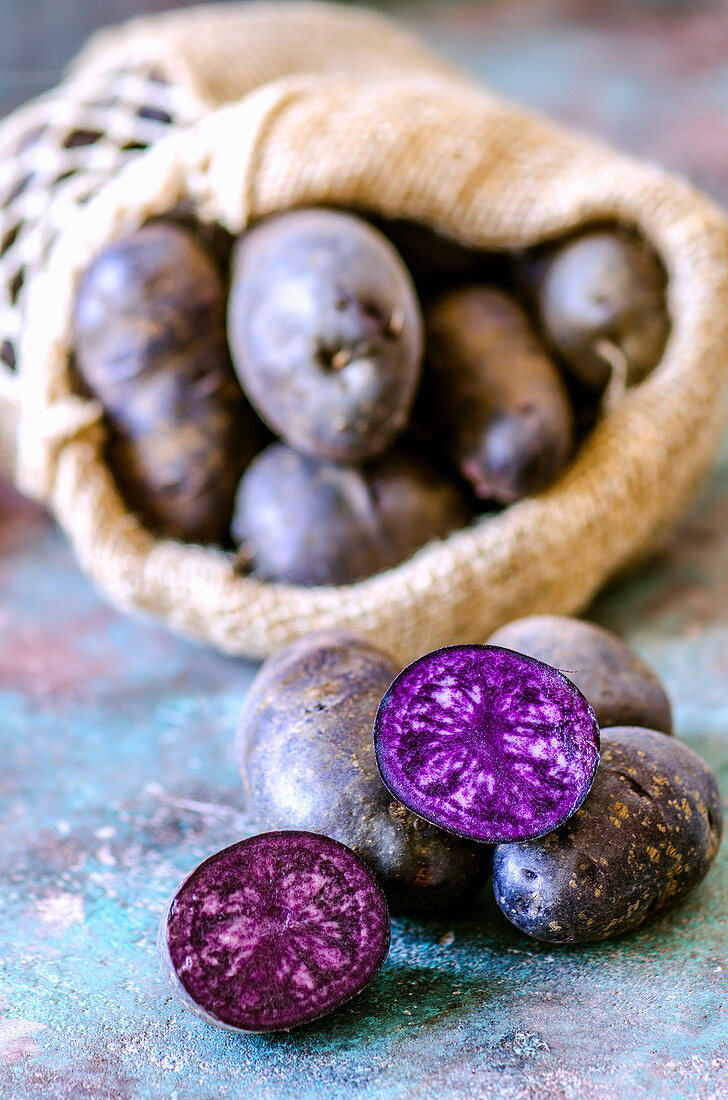 Violette Kartoffeln, ganz und halbiert, mit Jutesack