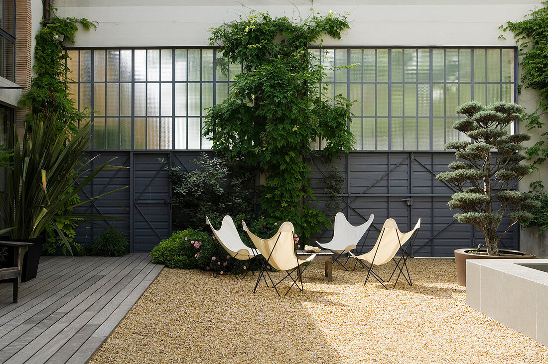 Group of designer Butterfly chairs and table in gravel courtyard