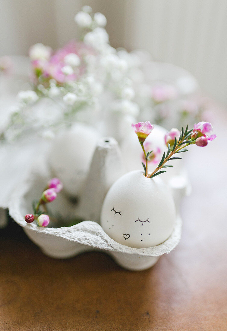 Flowers in a blown egg with a face