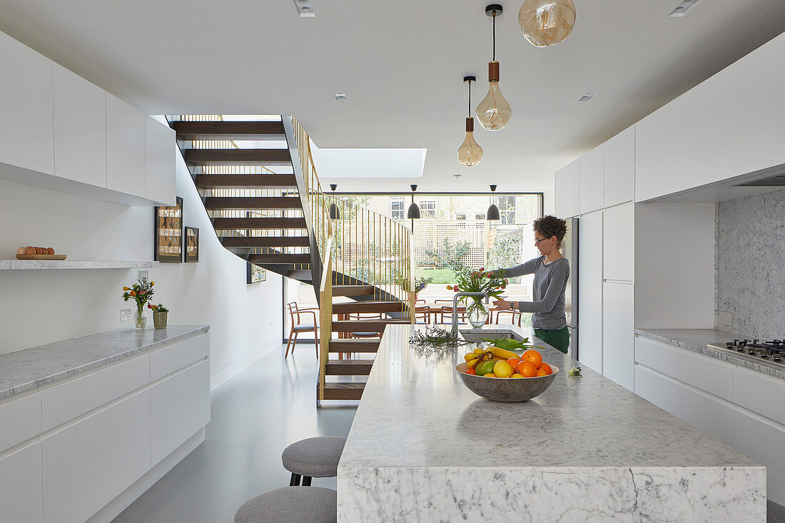 White, marble, minimalist kitchen with view into dining room