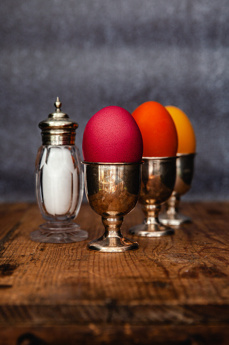 Easter eggs coloured with organic dyes in egg cups with a salt shaker