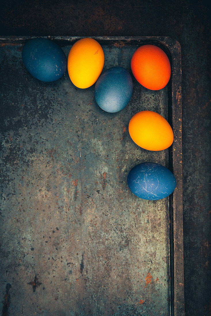 Easter eggs coloured with organic dyes on a vintage baking tray