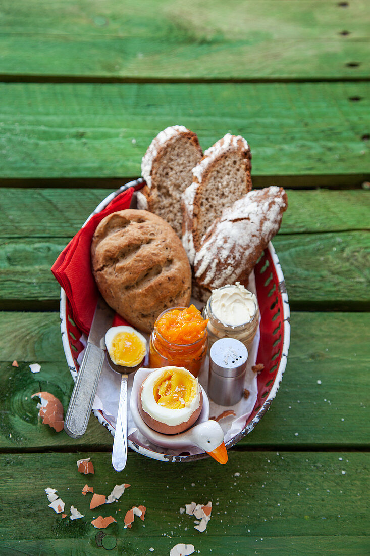 Frühstückskorb mit gekochtem Ei, Vollkorngebäck und Orangen-Karotten-Marmelade
