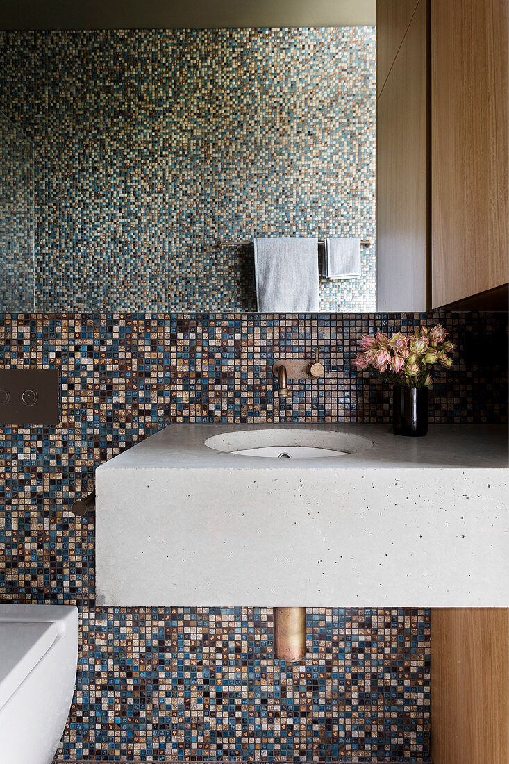 Concrete vanity in front of mosaic tiles in the bathroom
