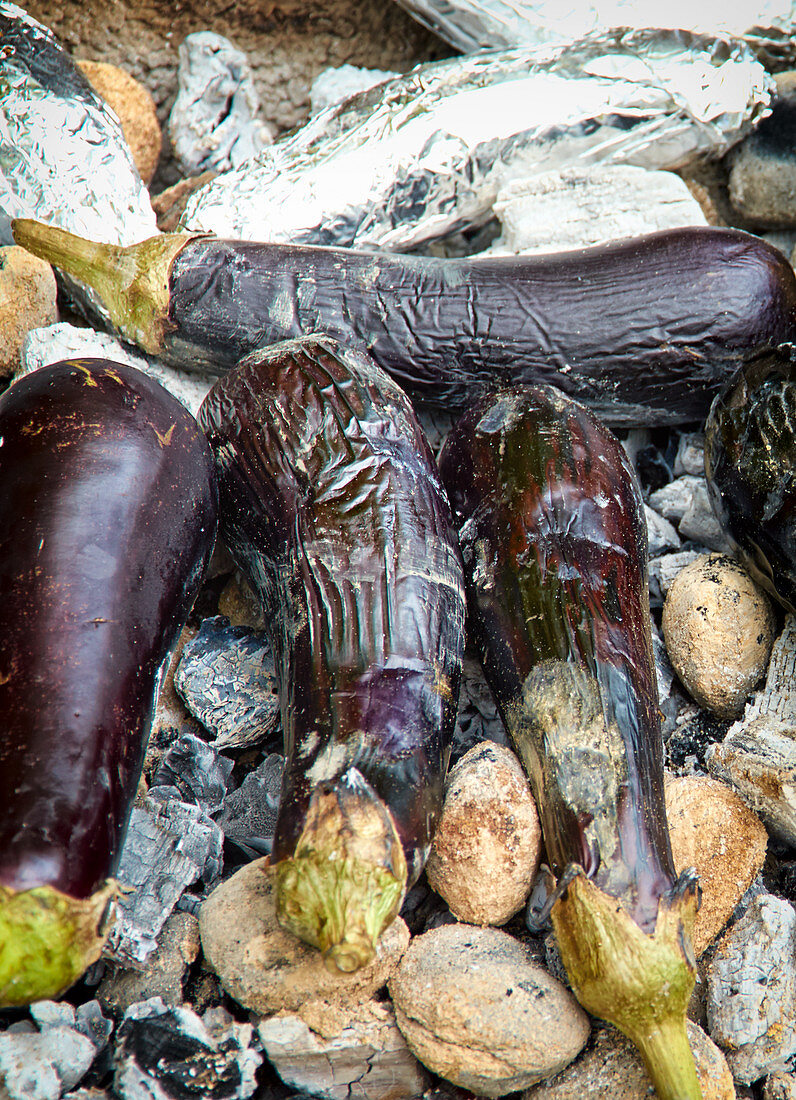 Whole aubergines on glowing coals