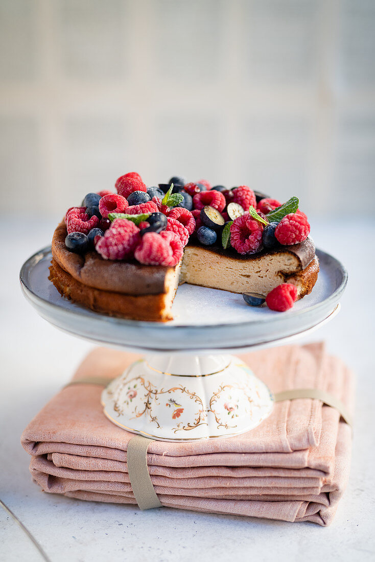 Käsekuchen mit Beeren, angeschnitten auf Kuchenständer