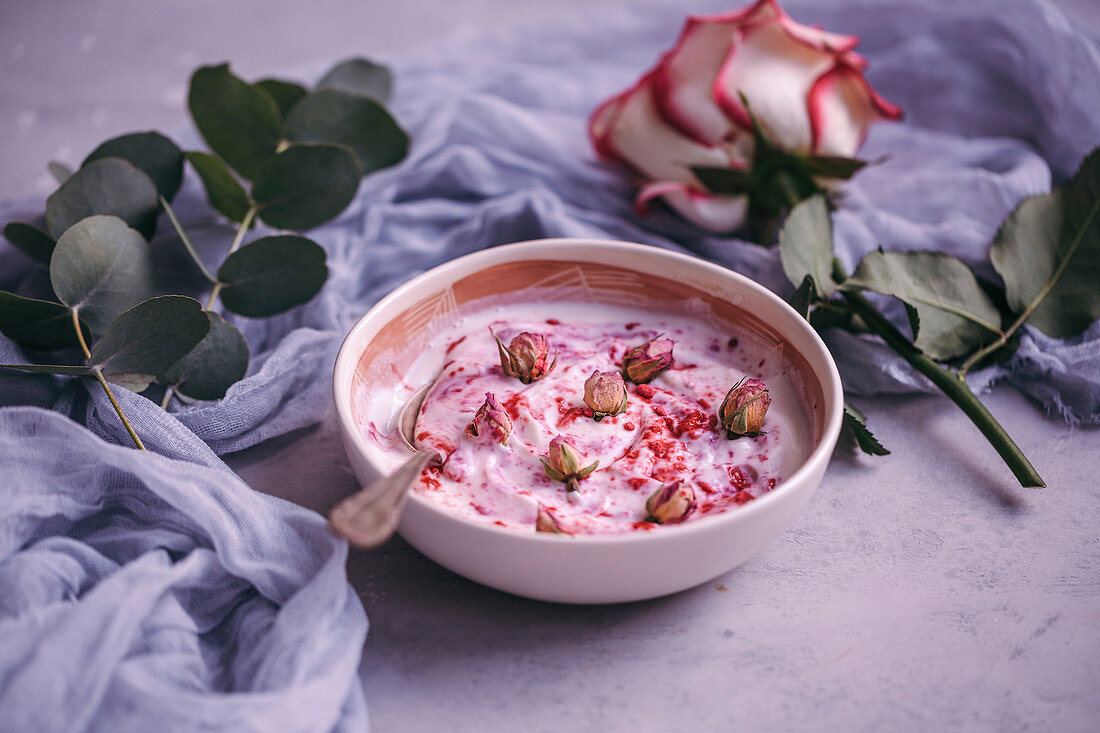 Bowl of yogurt with raspberry powder and dried rose buds