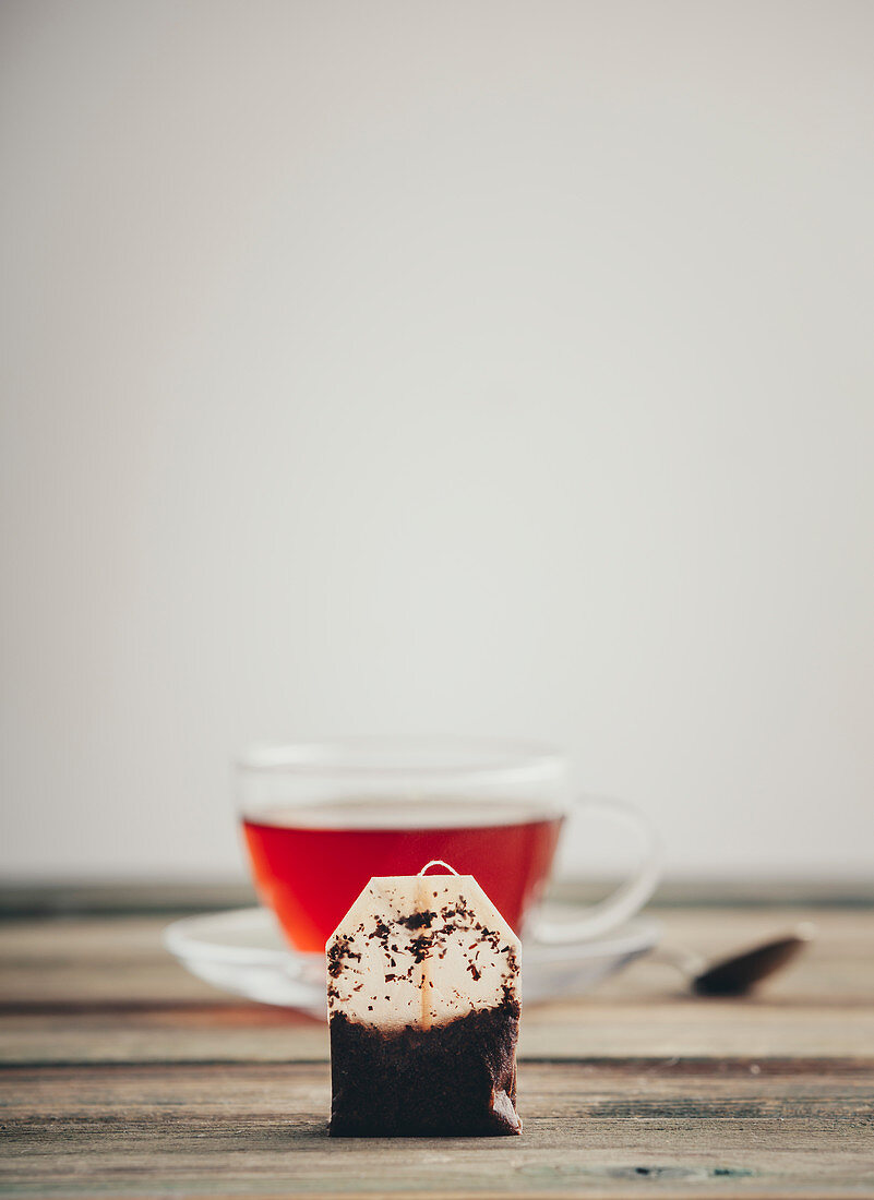 Used tea bag against a cup of tea